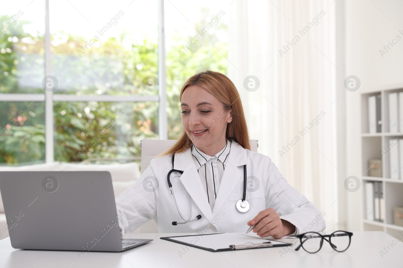 Photo of Doctor using laptop at table in clinic