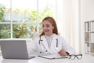 Photo of Doctor using laptop at table in clinic