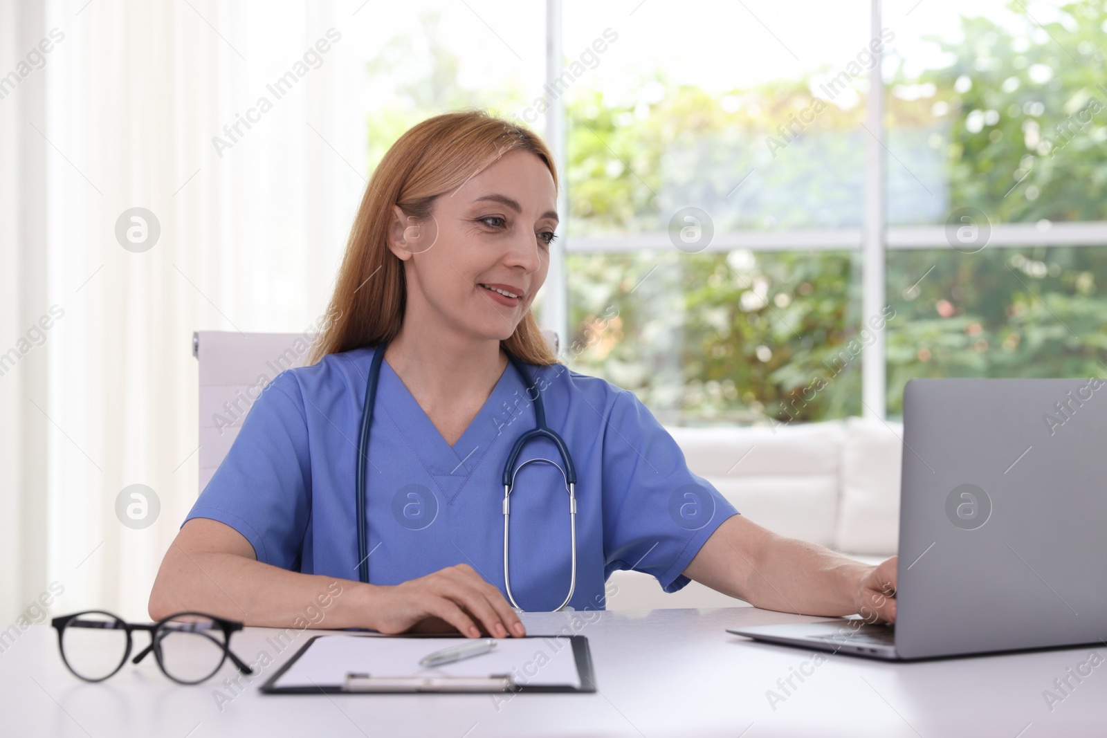 Photo of Doctor using laptop at table in clinic