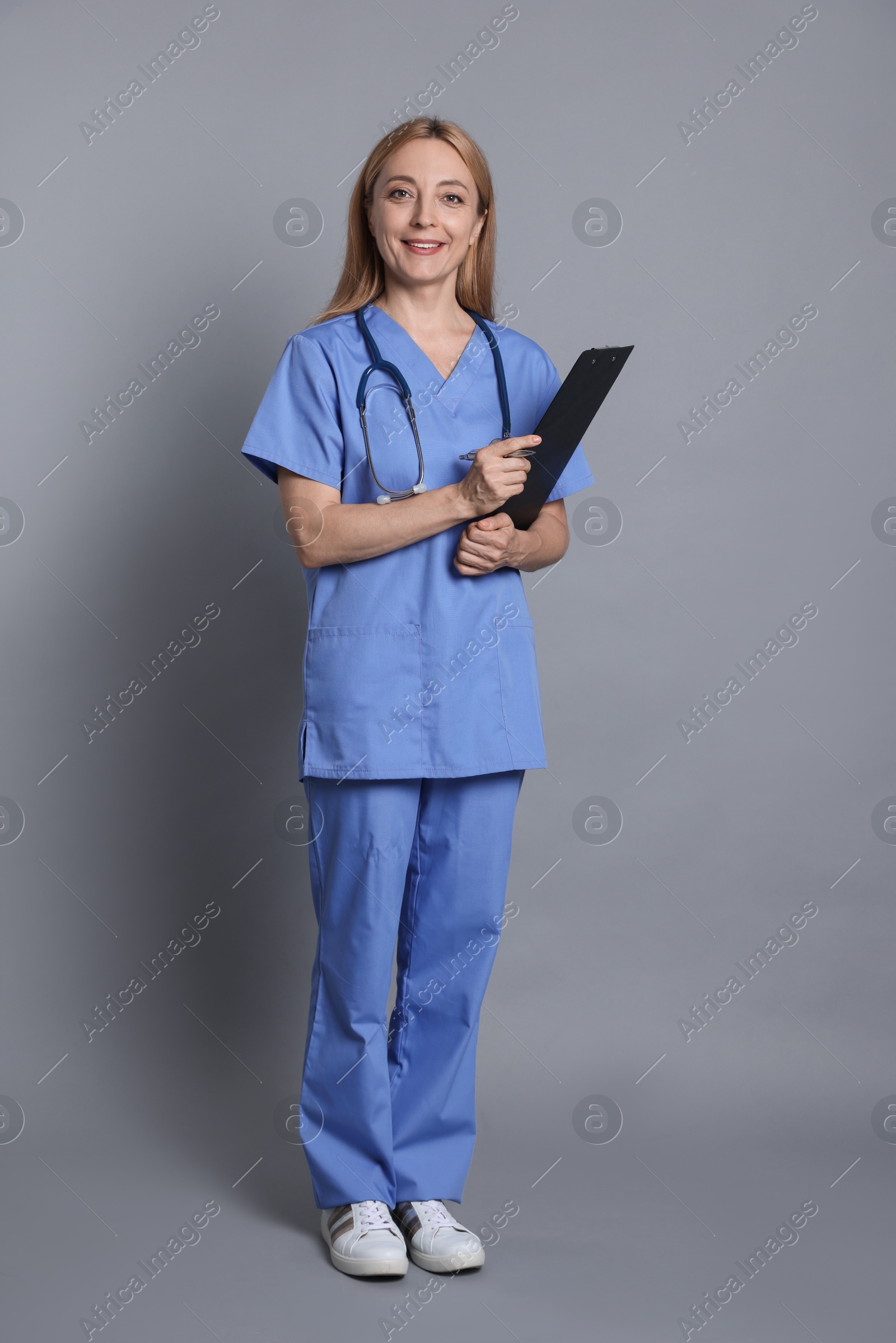 Photo of Doctor with stethoscope and clipboard on gray background