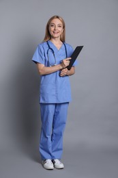 Doctor with stethoscope and clipboard on gray background