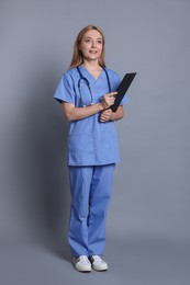 Photo of Doctor with stethoscope and clipboard on gray background