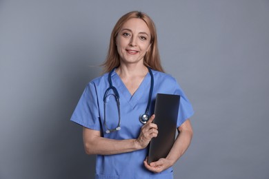 Photo of Doctor with stethoscope and laptop on gray background