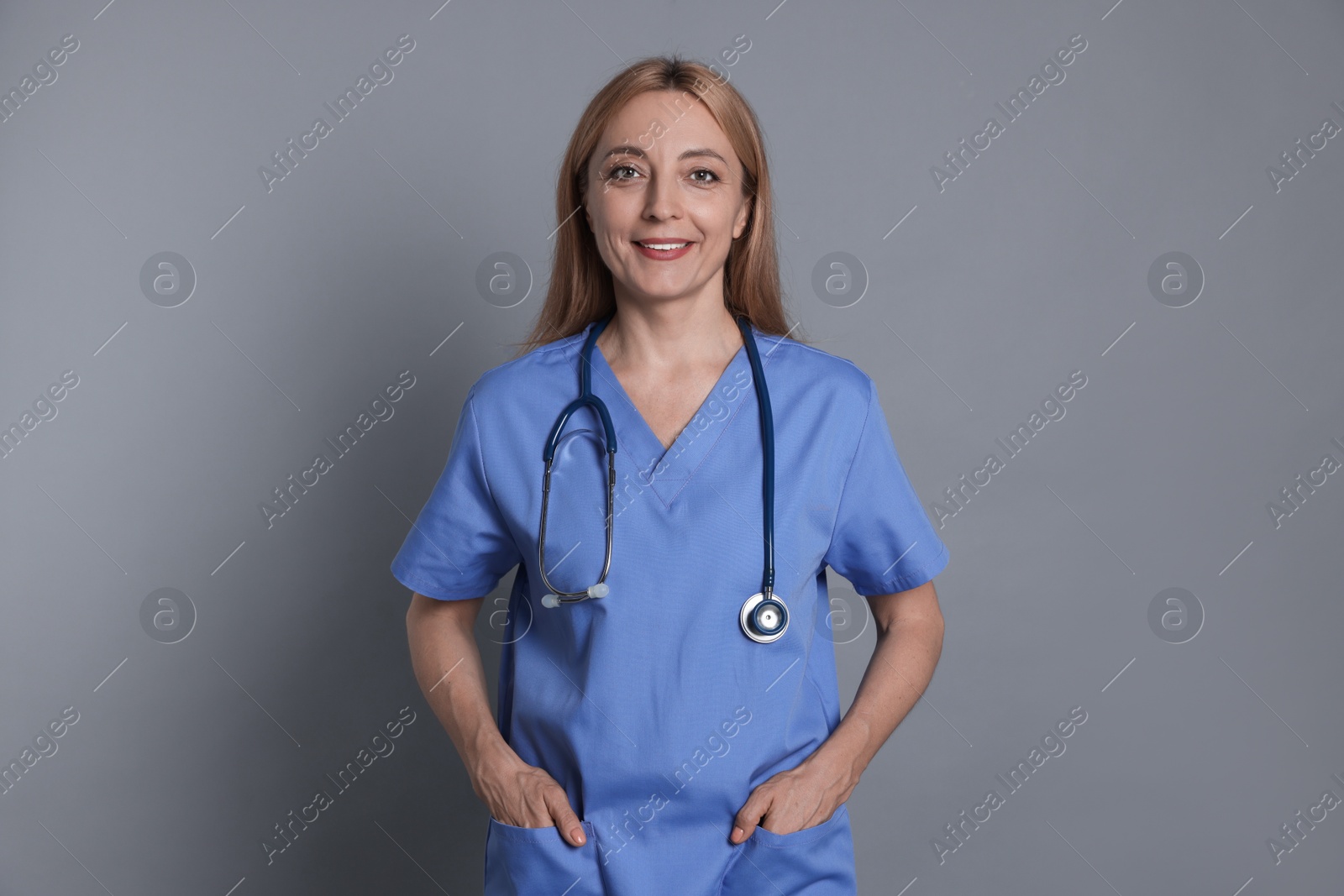 Photo of Smiling doctor with stethoscope on gray background