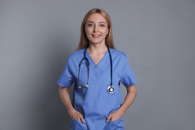 Photo of Smiling doctor with stethoscope on gray background