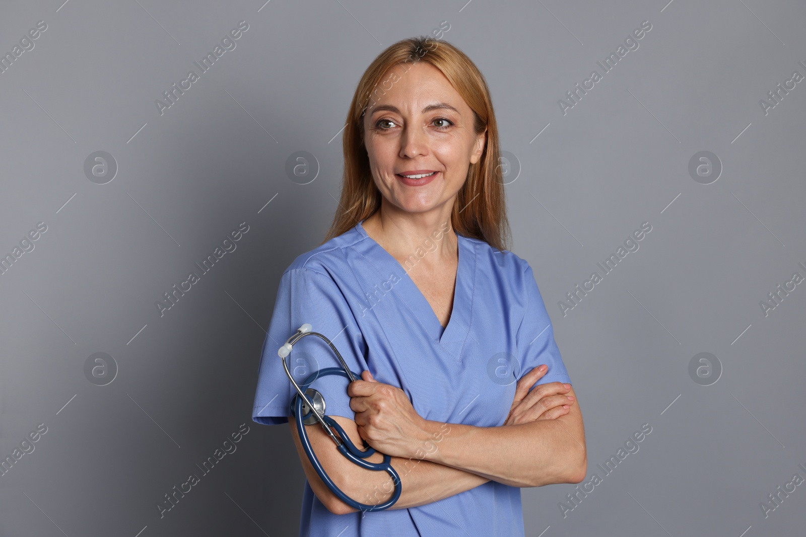 Photo of Smiling doctor with stethoscope on gray background