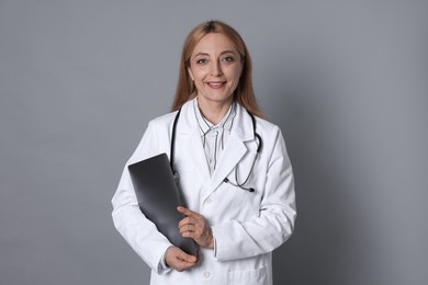 Photo of Doctor with stethoscope and laptop on gray background