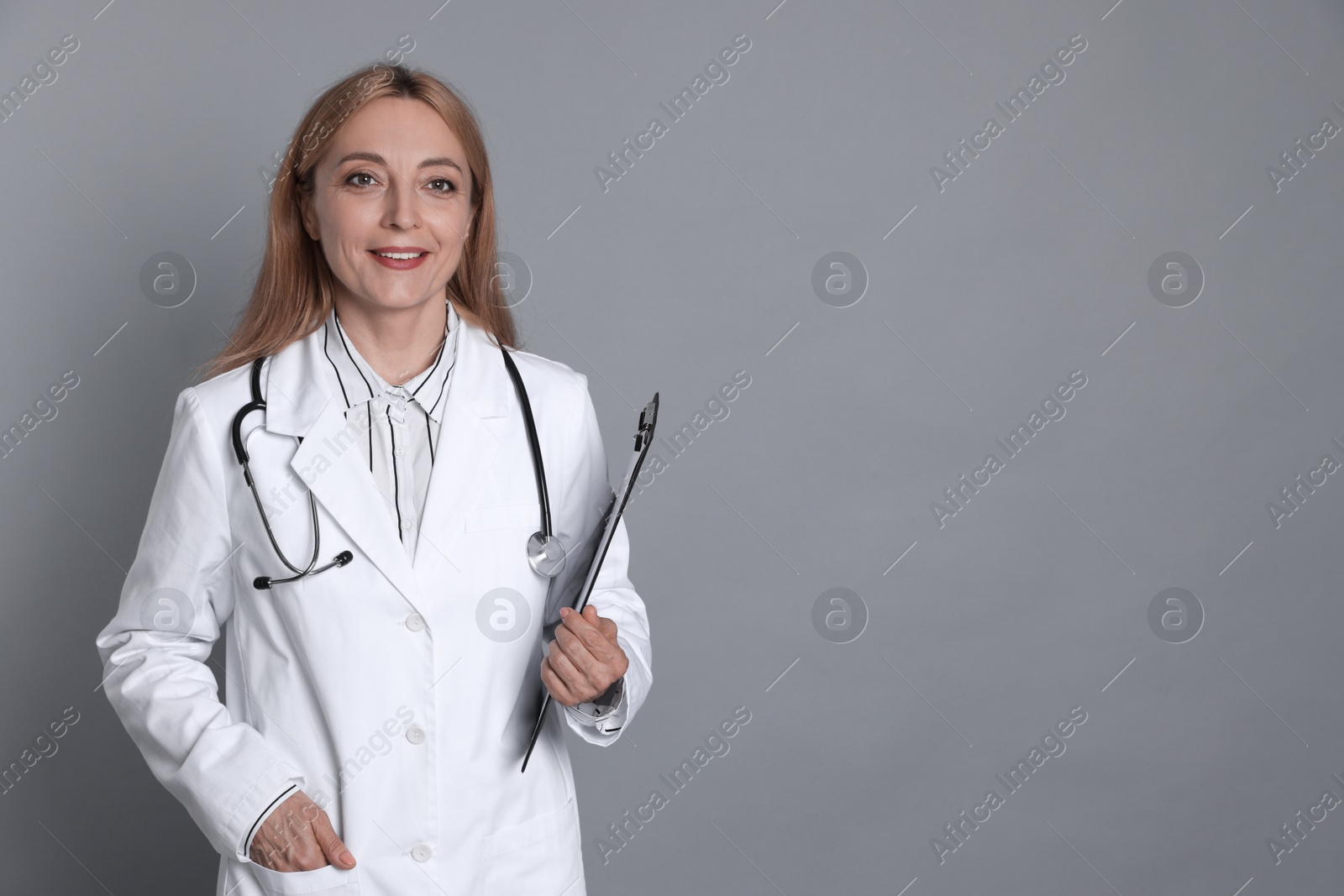 Photo of Doctor with stethoscope and clipboard on gray background, space for text