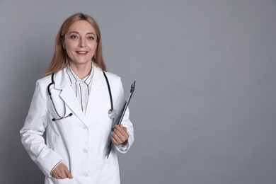 Photo of Doctor with stethoscope and clipboard on gray background, space for text