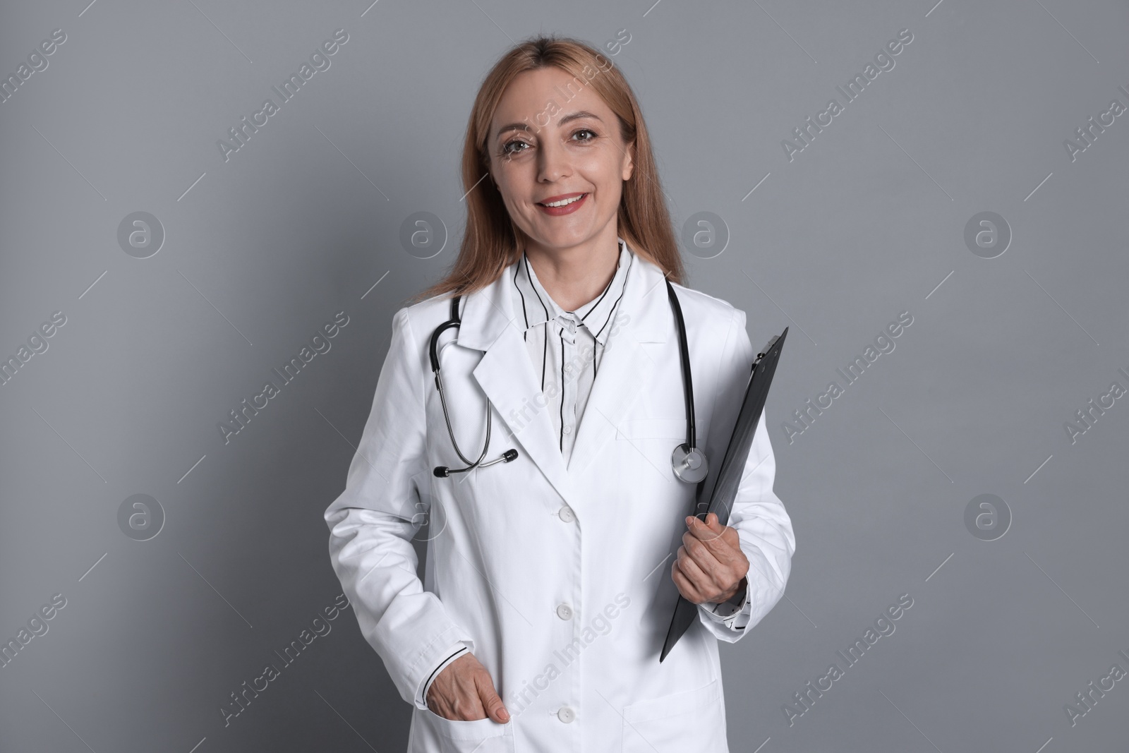 Photo of Doctor with stethoscope and clipboard on gray background