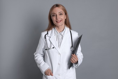 Photo of Doctor with stethoscope and clipboard on gray background