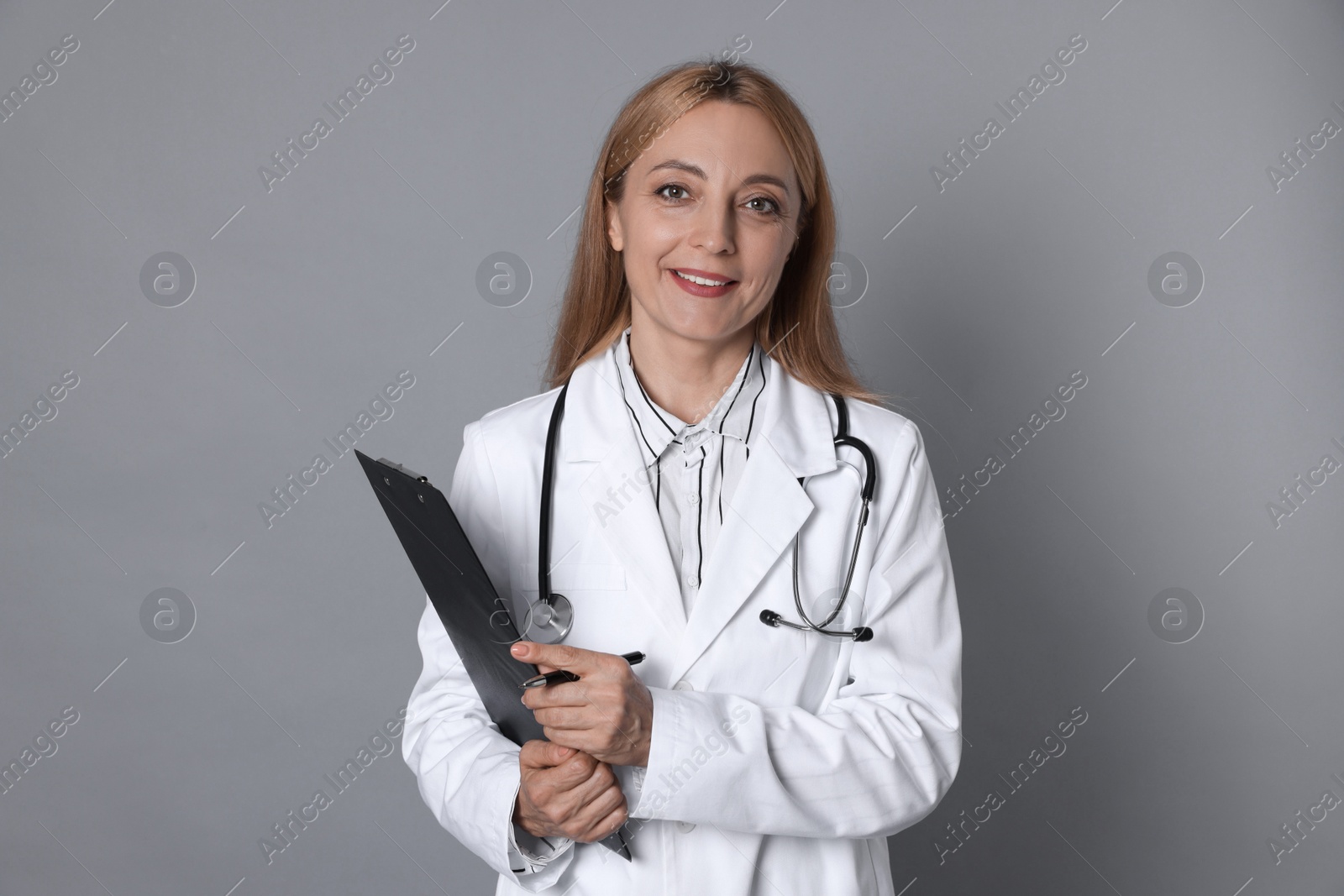 Photo of Doctor with stethoscope, clipboard and pen on gray background