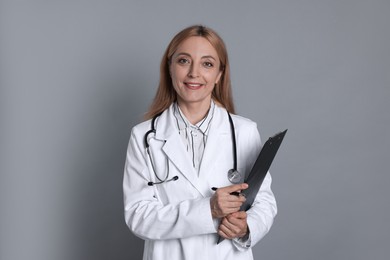 Photo of Doctor with stethoscope, clipboard and pen on gray background