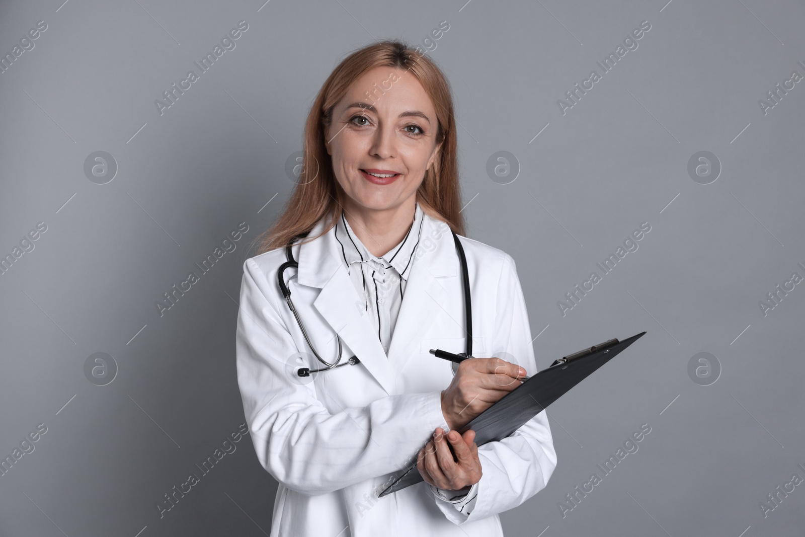 Photo of Doctor with clipboard writing notes on gray background