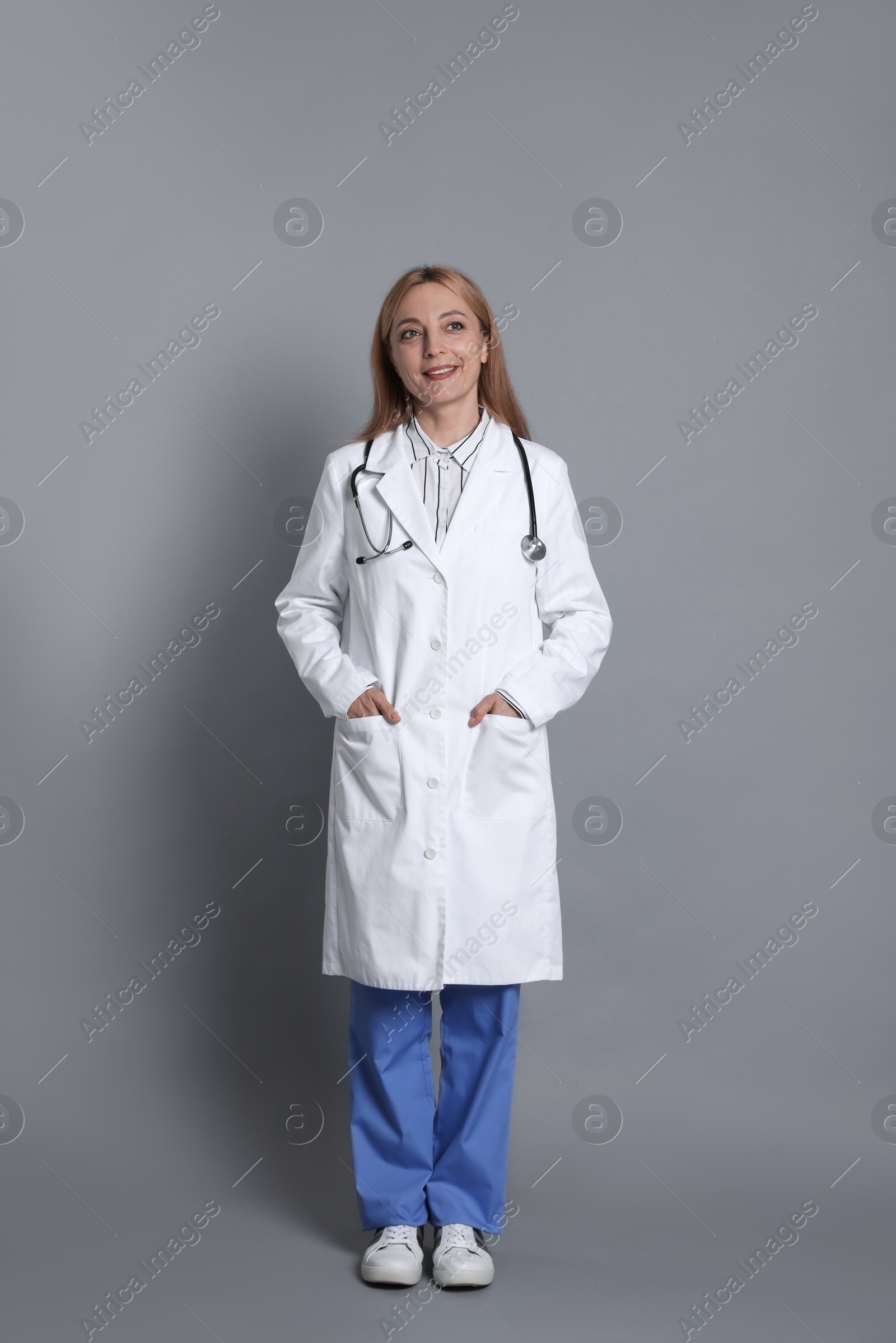 Photo of Smiling doctor with stethoscope on gray background