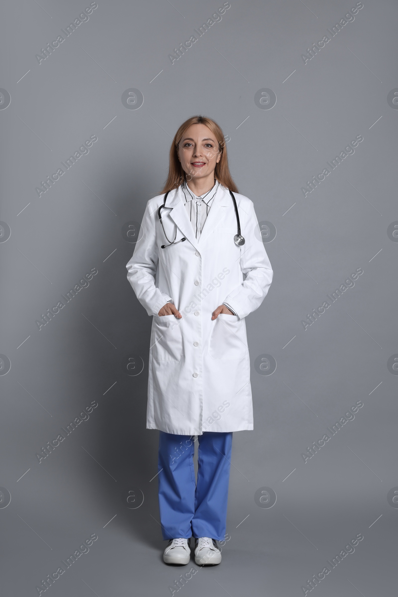 Photo of Smiling doctor with stethoscope on gray background