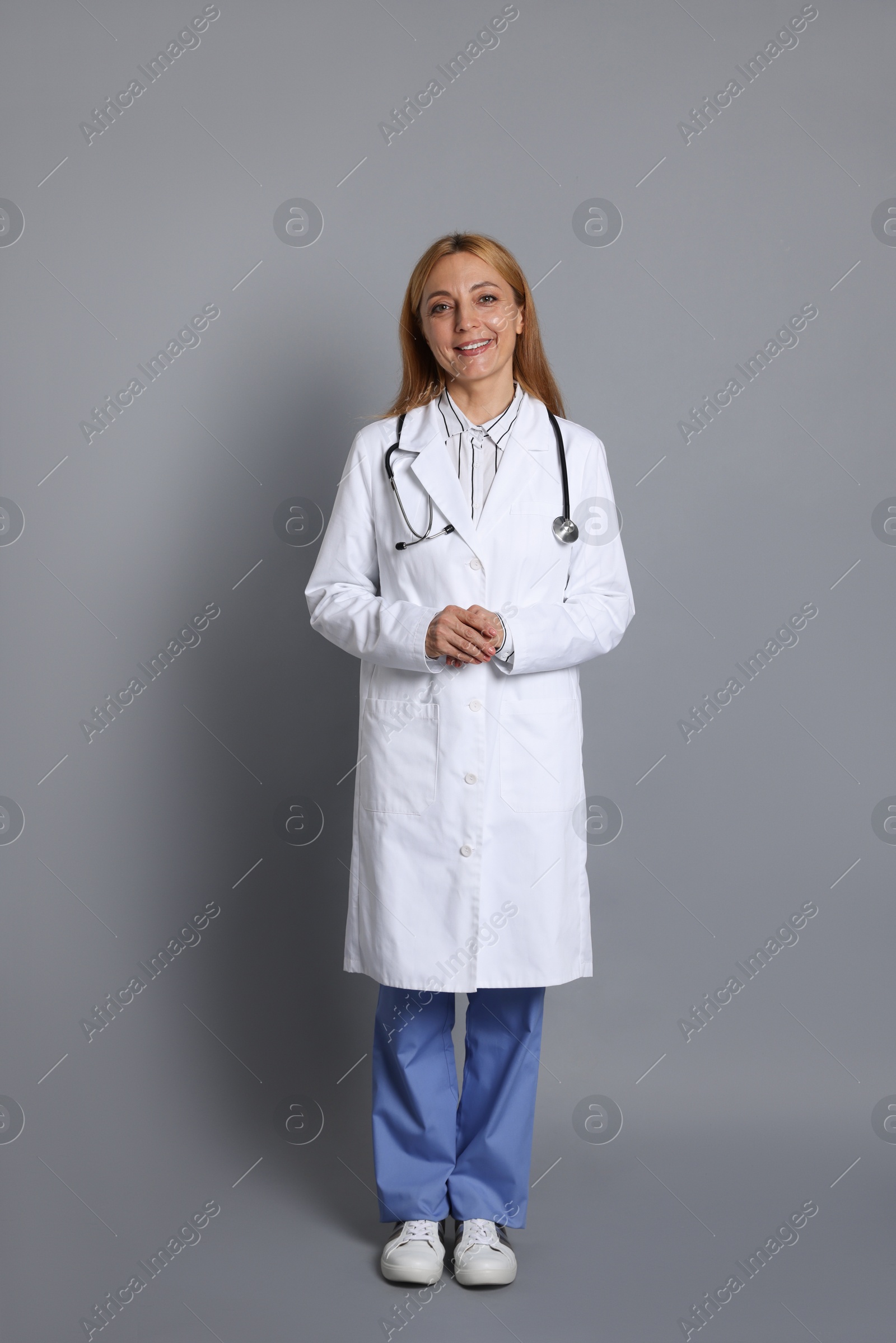 Photo of Smiling doctor with stethoscope on gray background