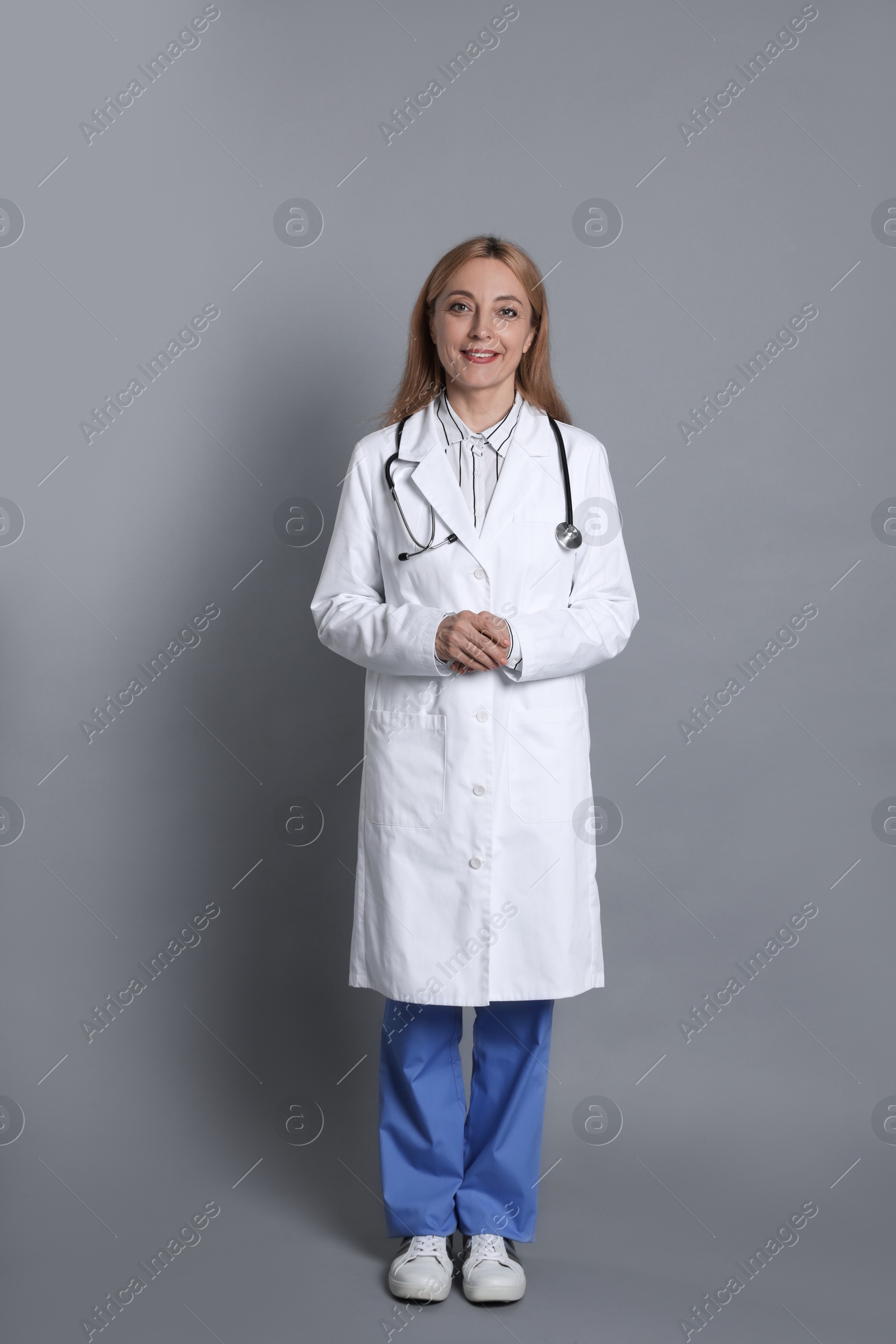 Photo of Smiling doctor with stethoscope on gray background