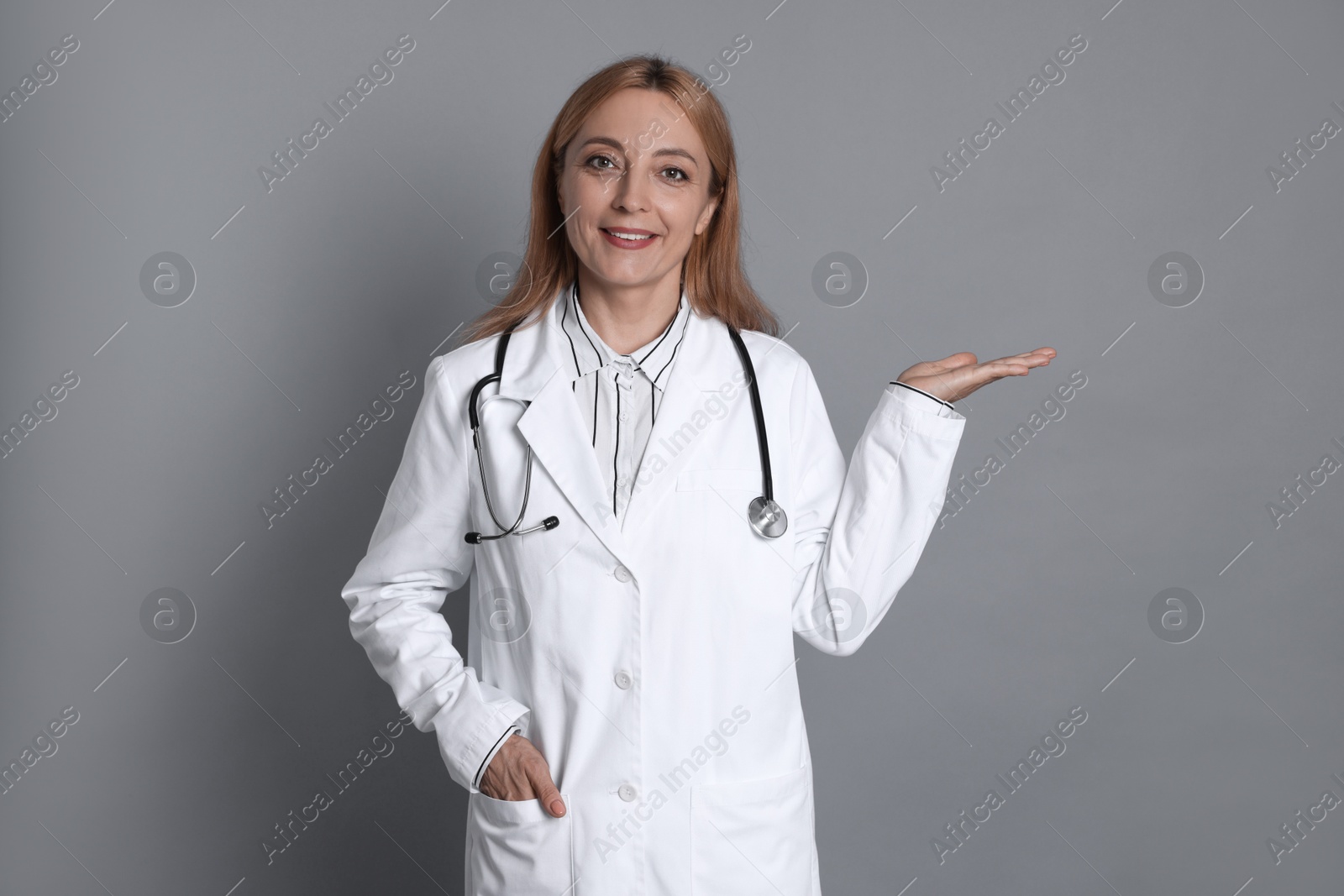 Photo of Doctor with stethoscope showing something on gray background