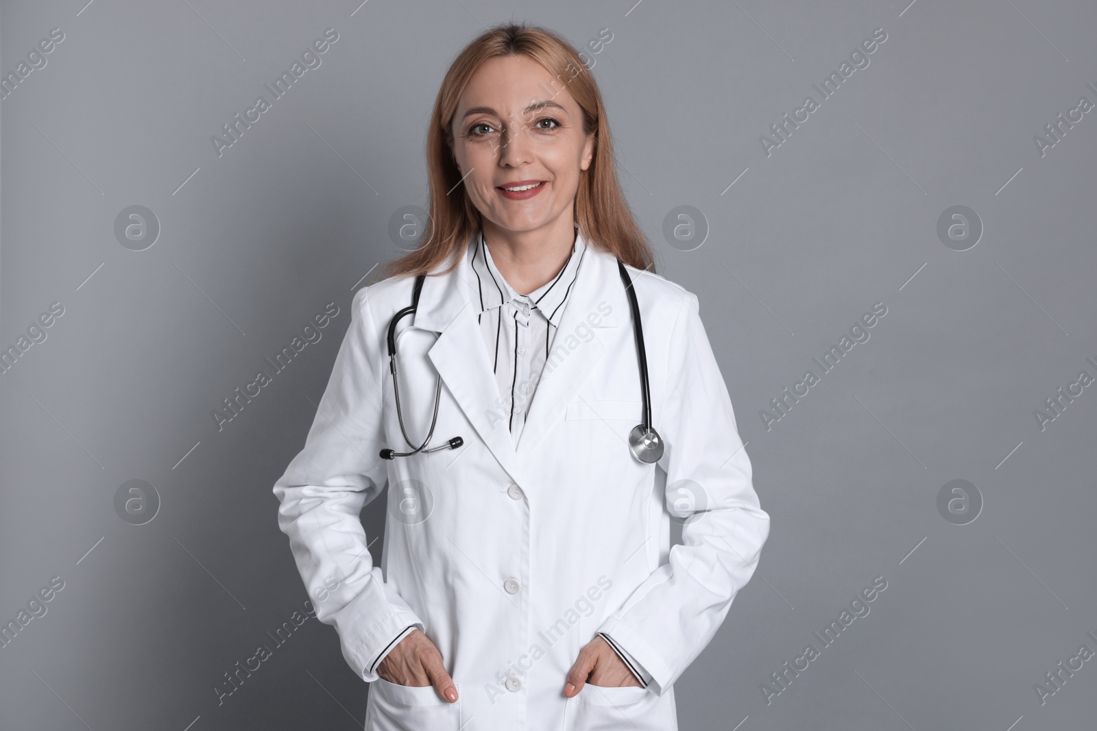 Photo of Smiling doctor with stethoscope on gray background