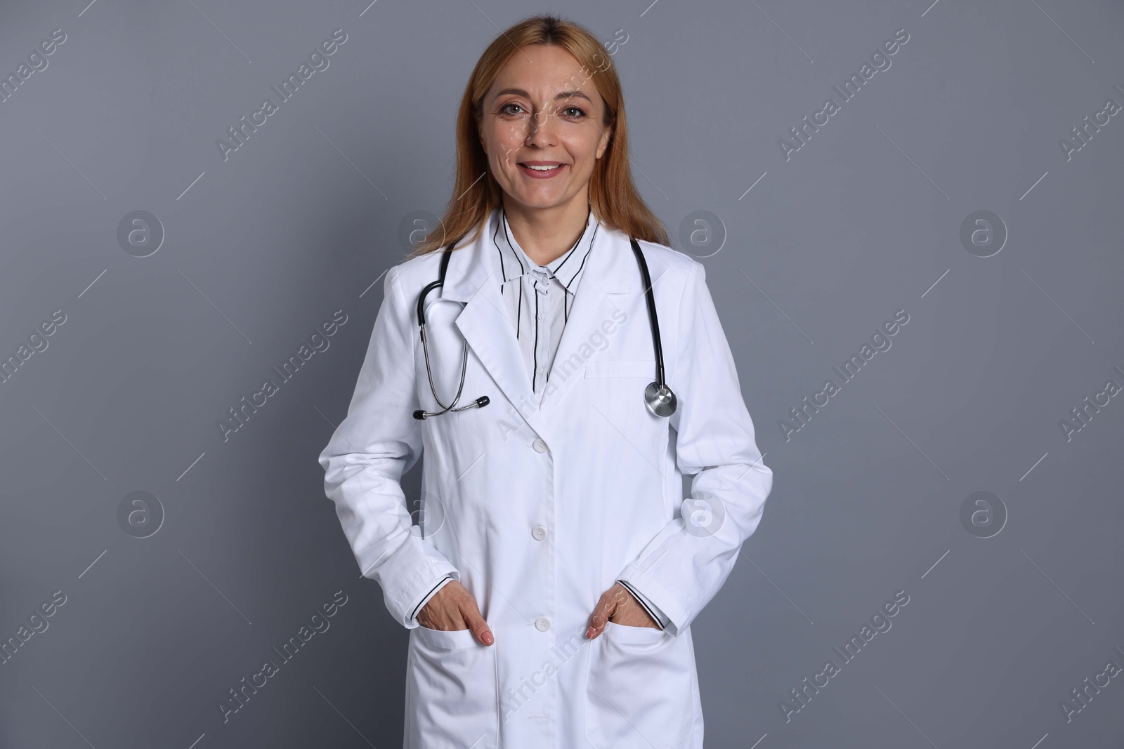 Photo of Smiling doctor with stethoscope on gray background