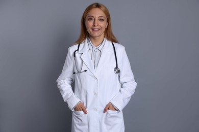 Smiling doctor with stethoscope on gray background