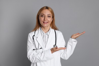 Photo of Doctor with stethoscope showing something on gray background