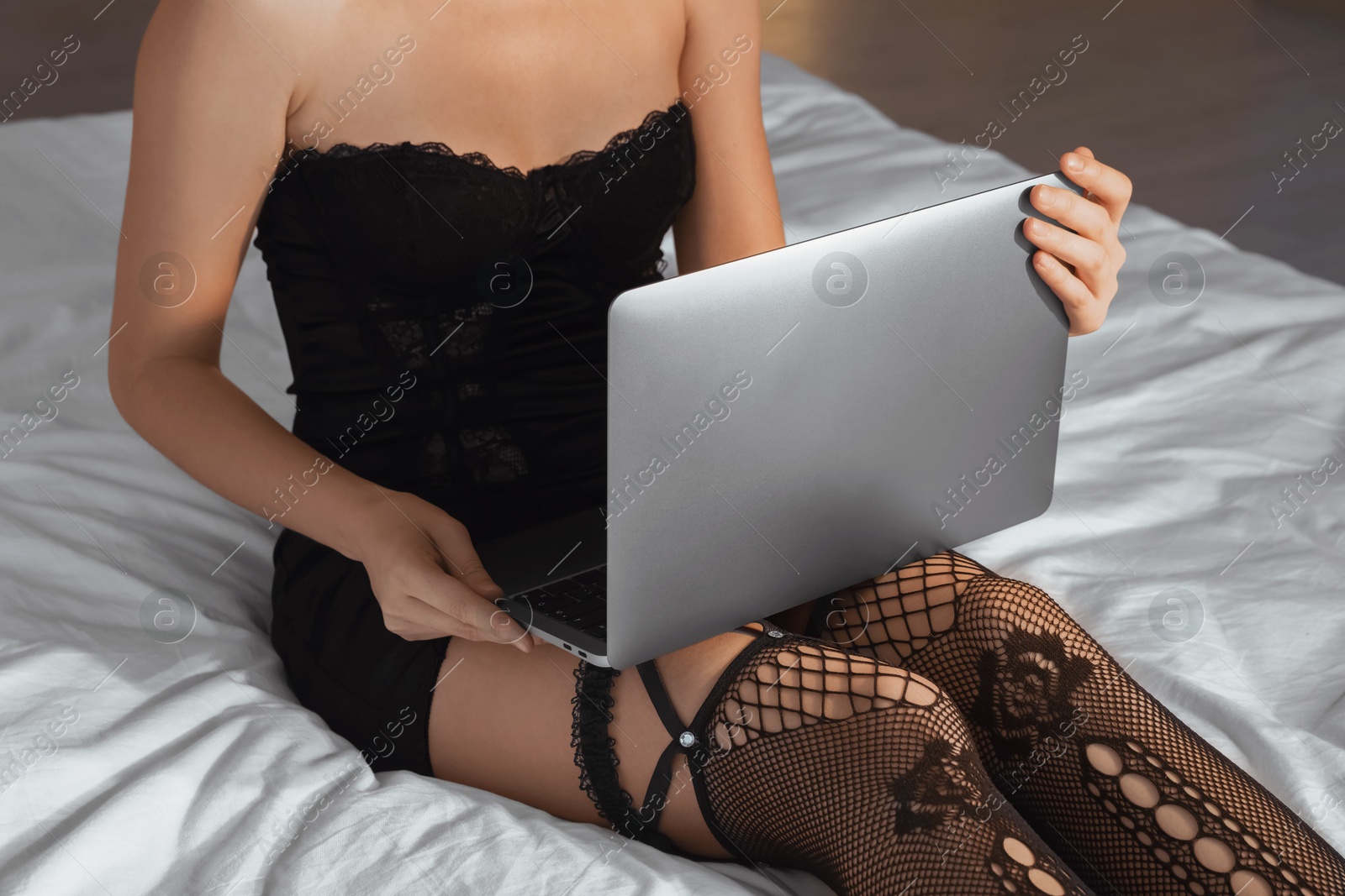 Photo of Prostitution. Webcam model streaming with laptop on bed, closeup