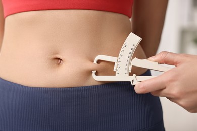 Photo of Doctor measuring woman's body fat with caliper in clinic, closeup