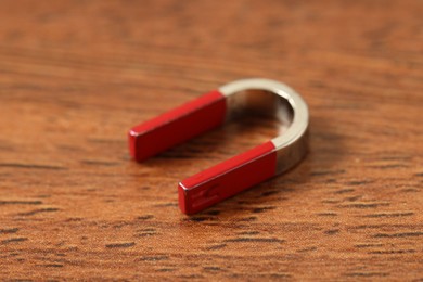 Photo of One horseshoe magnet on wooden table, closeup