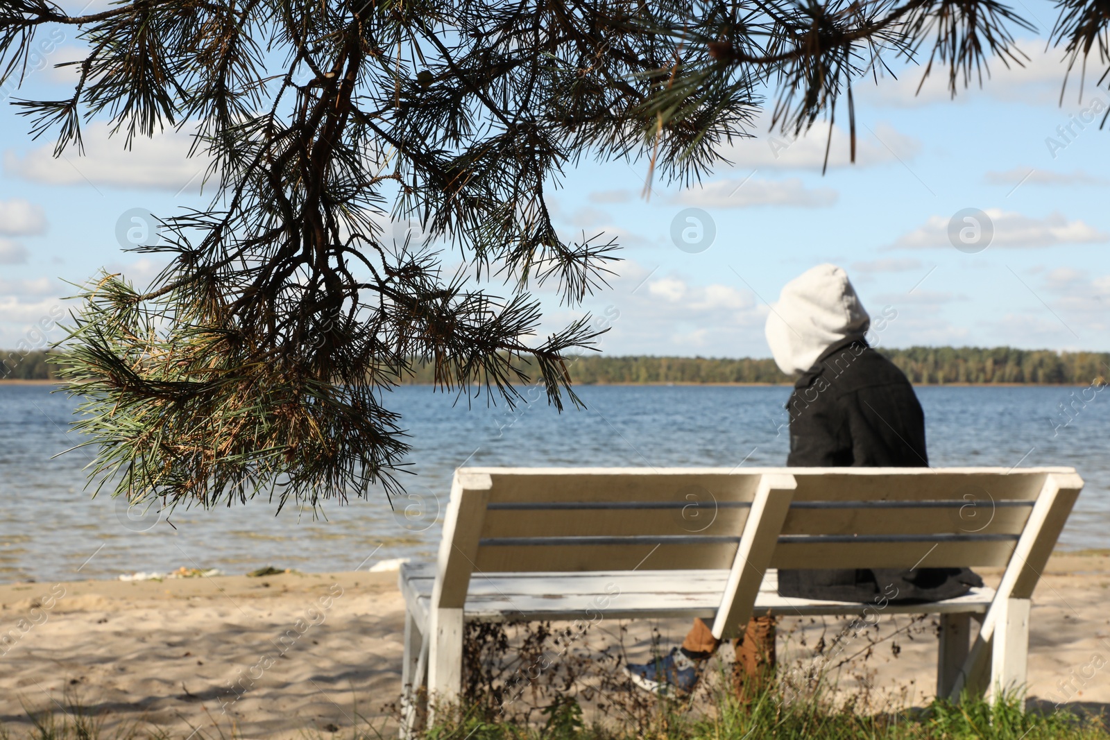 Photo of Loneliness concept. Sad man sitting on bench at riverside, selective focus