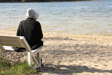 Photo of Loneliness concept. Sad man sitting on bench at beach