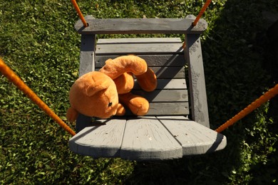 Photo of Lonely teddy bear on swing in park, above view