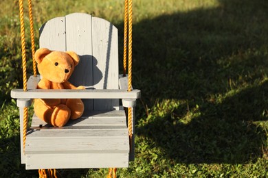 Photo of Lonely teddy bear on swing in park