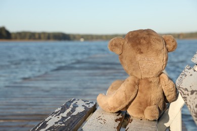 Photo of Lonely teddy bear on bench near river, space for text