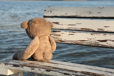 Photo of Lonely teddy bear on bench near river