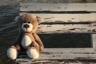 Photo of Lonely teddy bear on bench near river