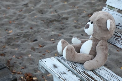 Photo of Lonely teddy bear on bench at beach