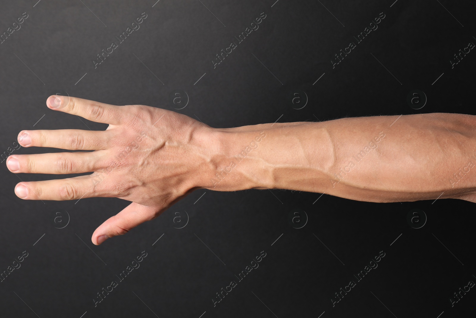 Photo of Man with bulging veins on his arm against black background, closeup