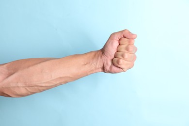 Photo of Man with bulging veins on his arm against light blue background, closeup