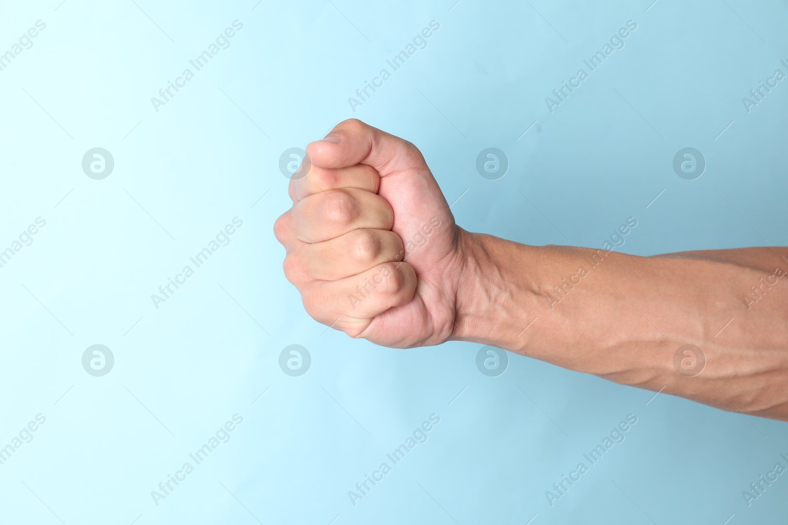 Photo of Man with bulging veins on his arm against light blue background, closeup