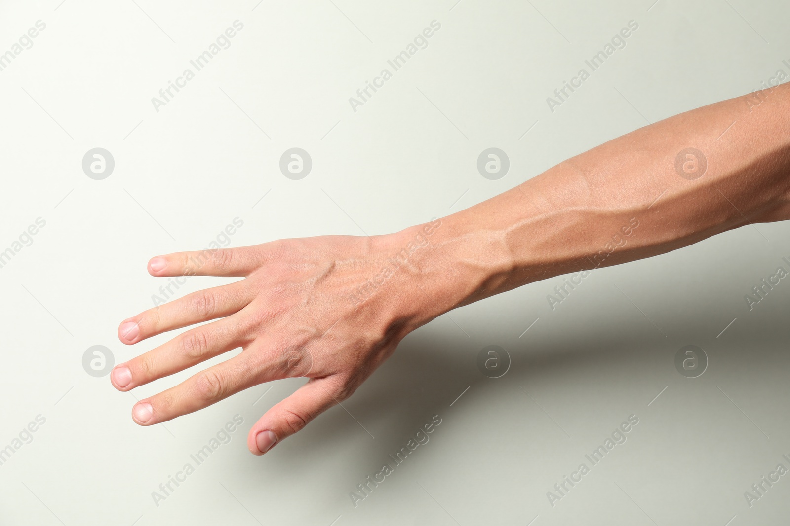 Photo of Man with bulging veins on his arm against light background, closeup