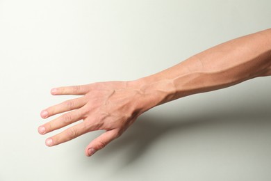 Photo of Man with bulging veins on his arm against light background, closeup