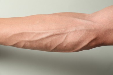 Photo of Man with bulging veins on his arm against light background, closeup