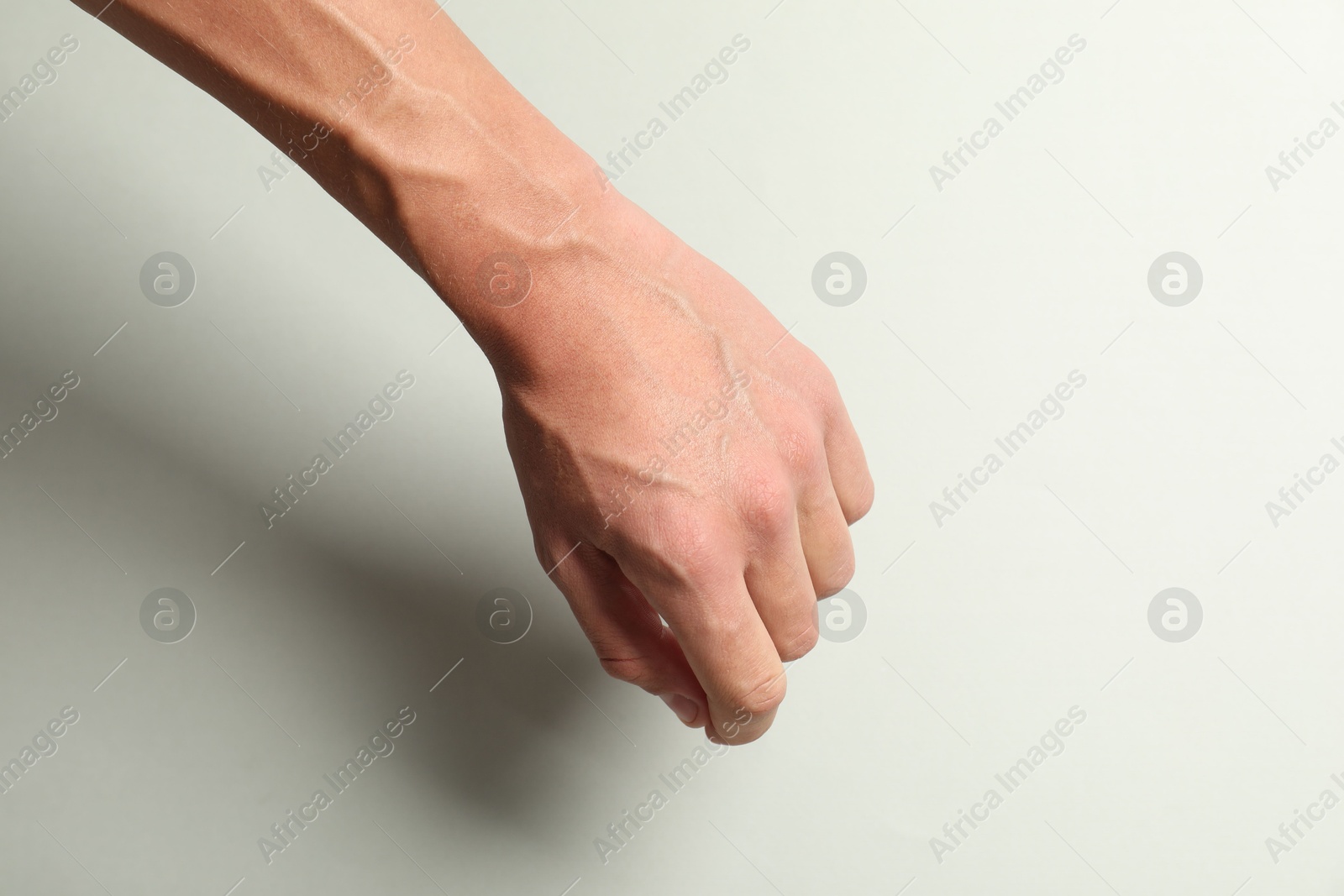 Photo of Man with bulging veins on his arm against light background, closeup