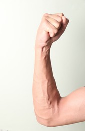 Photo of Man with bulging veins on his arm against light background, closeup