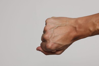 Photo of Man with bulging veins on his arm against light background, closeup. Space for text