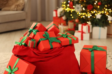 Photo of Santa bag full of Christmas presents at home, closeup