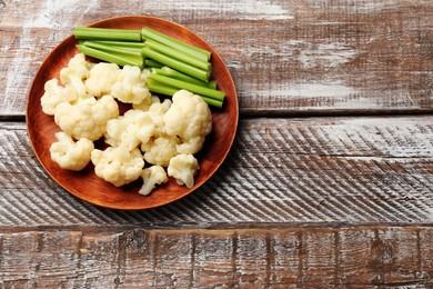 Photo of Tasty cauliflower with celery on wooden table, top view. Space for text