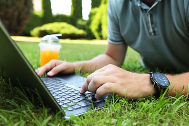 Man using laptop on green lawn outdoors, closeup